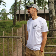 Iloinen mies luonnossa jolla päällä valkoinen t-paita jossa pieni hirvipainatus